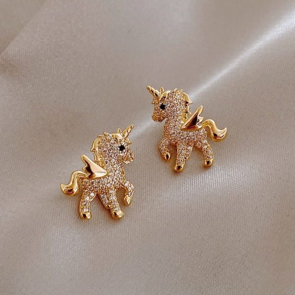 Boucles d'oreilles licorne à strass posées sur un tissu satiné
