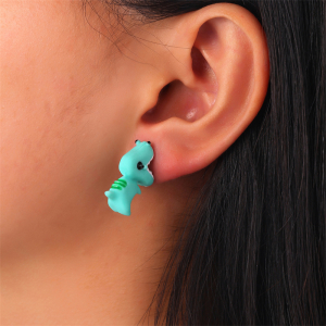 Boucle d'oreille verte en forme de dinosaure portée par une femme