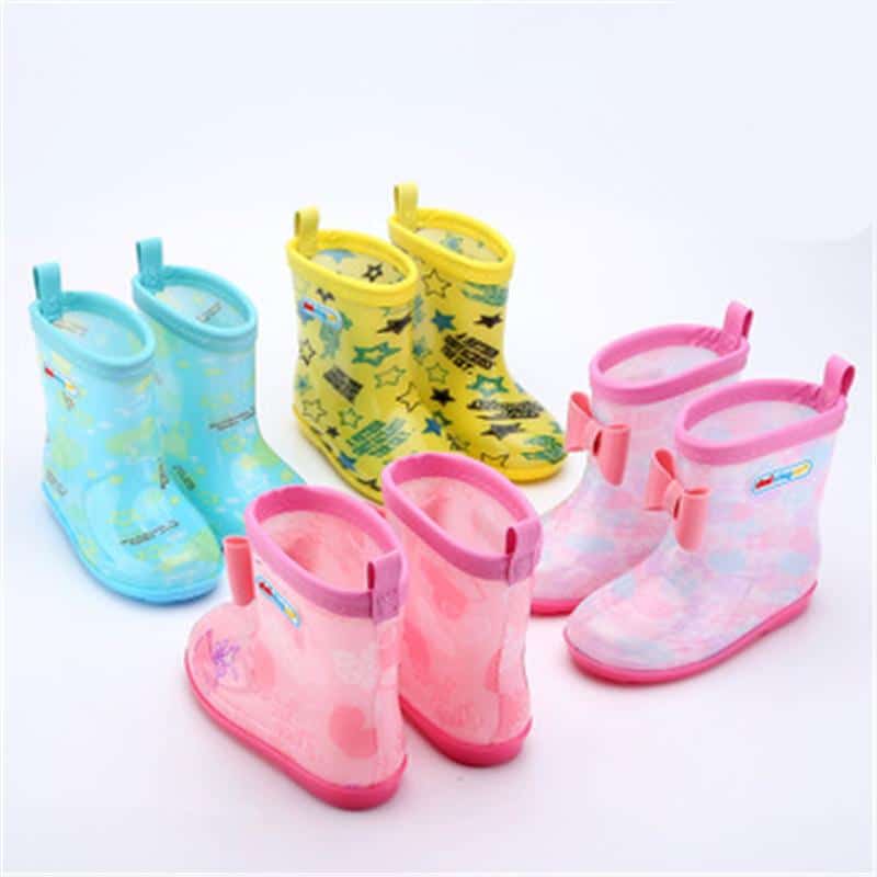 quatre paires de bottes de pluie pour enfant sont mises ensemble sur un fond blanc. Les bottes sont bleues, jaunes, roses et violets