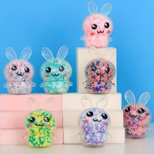 Balle anti-stress à billes en forme de lapin squishy (lot de 3). Les lapins sont en plastique extensible transparent. A l'intérieur des petites billes de couleur. On y voit 7 lapins, le fond est bleu et certains lapins sont sur des supports.