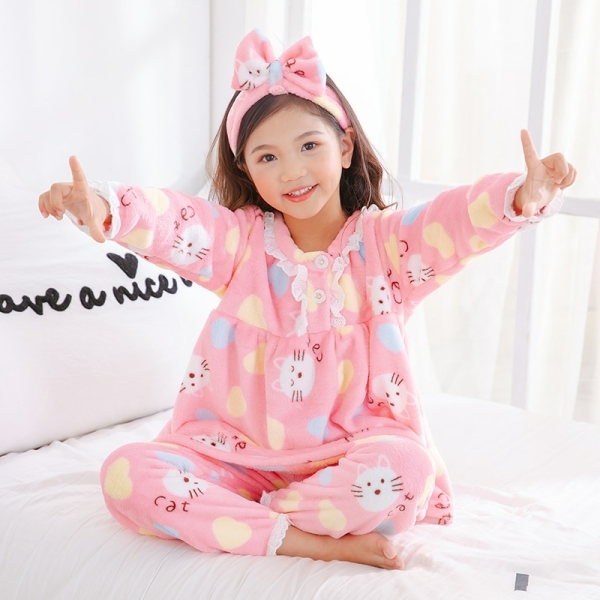 Pyjama polaire avec un bandeau cheveux pour filles roses porté par une petite fille sur une lot dans une maison