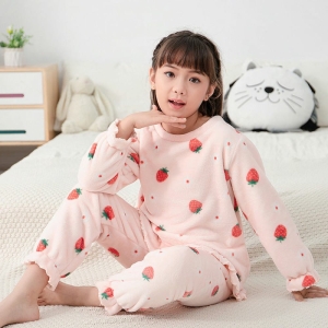 Pyjama polaire chaud rose à motif mignon pour filles porté par une petite fille sur une lit dans une maison