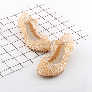 Sandale pour fille de couleur beige posée sur un papier quadrillé et un sol blanc