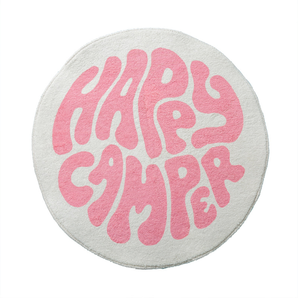 Un tapis rond pour chambre de fille blanc et rose. Avec l'inscription happy camper au centre.