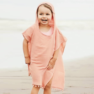 Tenue de plage pour fille avec capuche de couleur rose portée par une fille à la plage