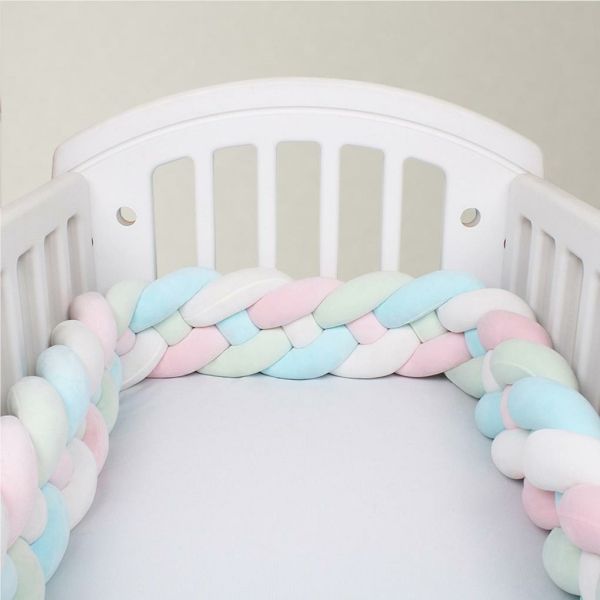 Tour de lit bébé tressé multicolore pour fille avec un fond un lit de bébé