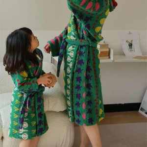 Jeune fille brune avec une personne adulte dans une pièce, toutes deux portant un peignoir vert à motifs légumes