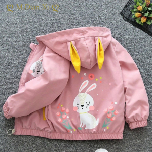Manteau rose motif lapin posé à plat sur un tissu gris