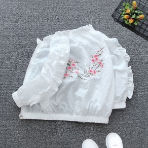 Veste blanche à volants avec motif floral, posée à plat montrant le dos