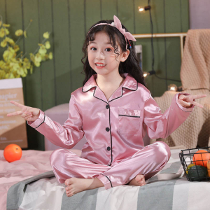 Jeune fille assise en tailleur en pyjama satiné rose