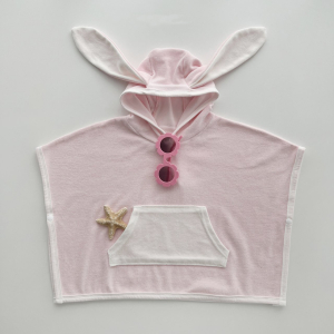 Peignoir rose à capuche et oreilles de lapin avec poches sur le devant et lunettes de soleil accrochées au col et une étoile de mer en décoration