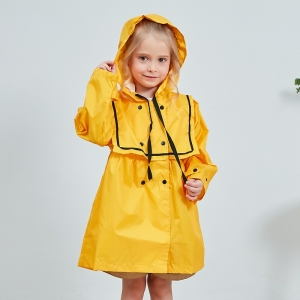 Petite fille blonde souriante, debout, portant un ciré à capuche jaune