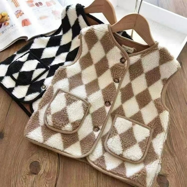 2 gilets sans manches motifs losanges sur des cintres, posés à plat sur du bois