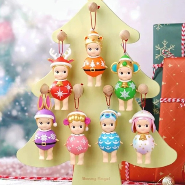 7 figurines Sonny Angel suspendues sur un sapin de Noël beige, avec un fond décoré en Noël