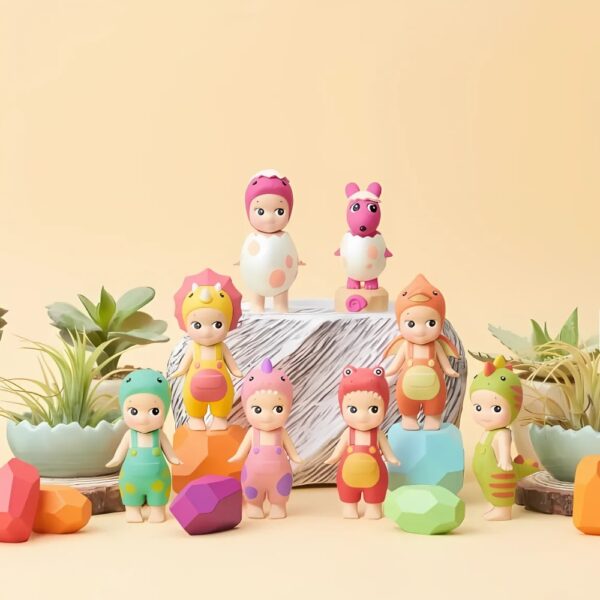 Figurines Sonny Angel de la collection "Dinosaure". Chaque figurine est habillée en costume de dinosaure coloré avec des détails amusants comme des écailles, des cornes ou des motifs d'œufs, posés dans un décor naturel avec des plantes et des rochers multicolores.