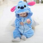 bébé assis au sol, portant une combinaison Stitch bleue à capuche avec oreilles et dents sur la capuche, dans une chambre au ton blanc