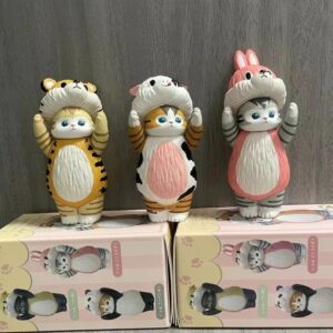 Ffigurines de chats Mofusand, l’une déguisée en panda, l’autre en ourson, tenues à la main avec leurs pattes levées et une expression mignonne.