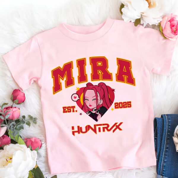 T-shirt fille K-pop Demon Hunters rose du personnage Mira. Son prénom et Huntrix sont écrits en majuscules rouge. Entre les deux, le visage de Mira version cartoon. Le t-shirt est posé à côté de fleurs.