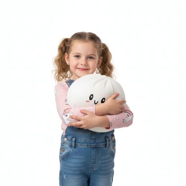 Jeune fille debout avec des couettes, portant un jean et un t-shirt rose, qui tient dans ses bras un squishy dumpling blanc.