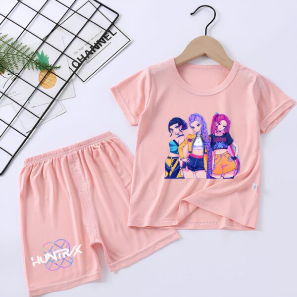 Un Ensemble short et t-shirt K-pop Demon Hunters Fille beige avec un t-shirt rose et un short assorti, décoré de trois personnages colorés au centre, sur fond gris